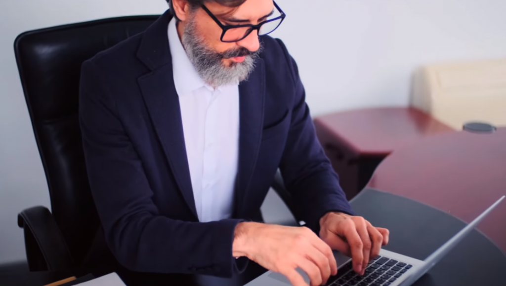 Senior man with glasses sitting in front of a laptop