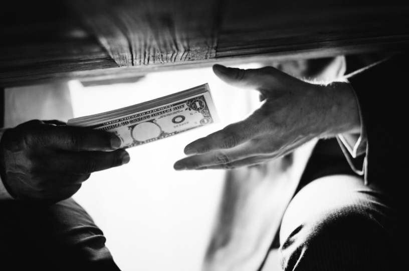 Hands passing money under the table corruption and bribery
