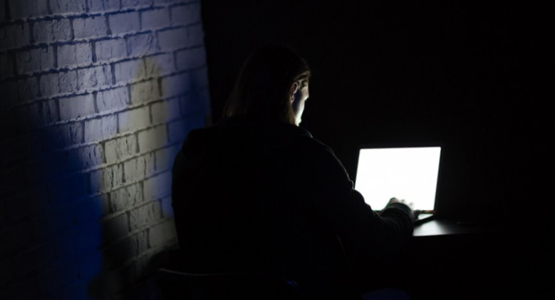 Back view of young concentrated man using laptop