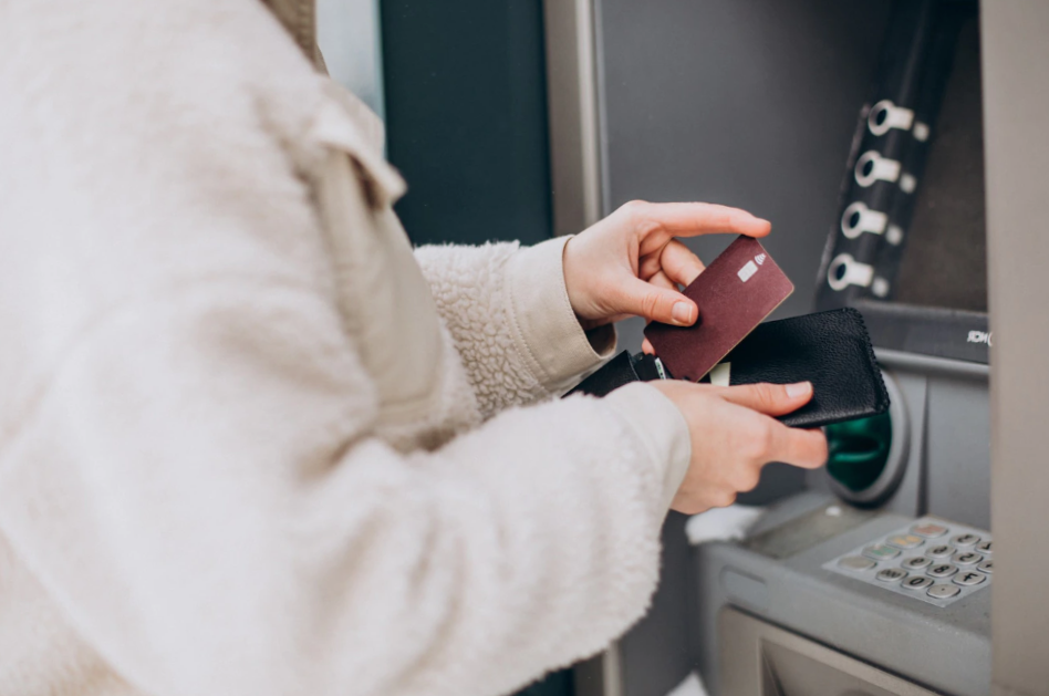 Woman withdrawing money at atm outside the street